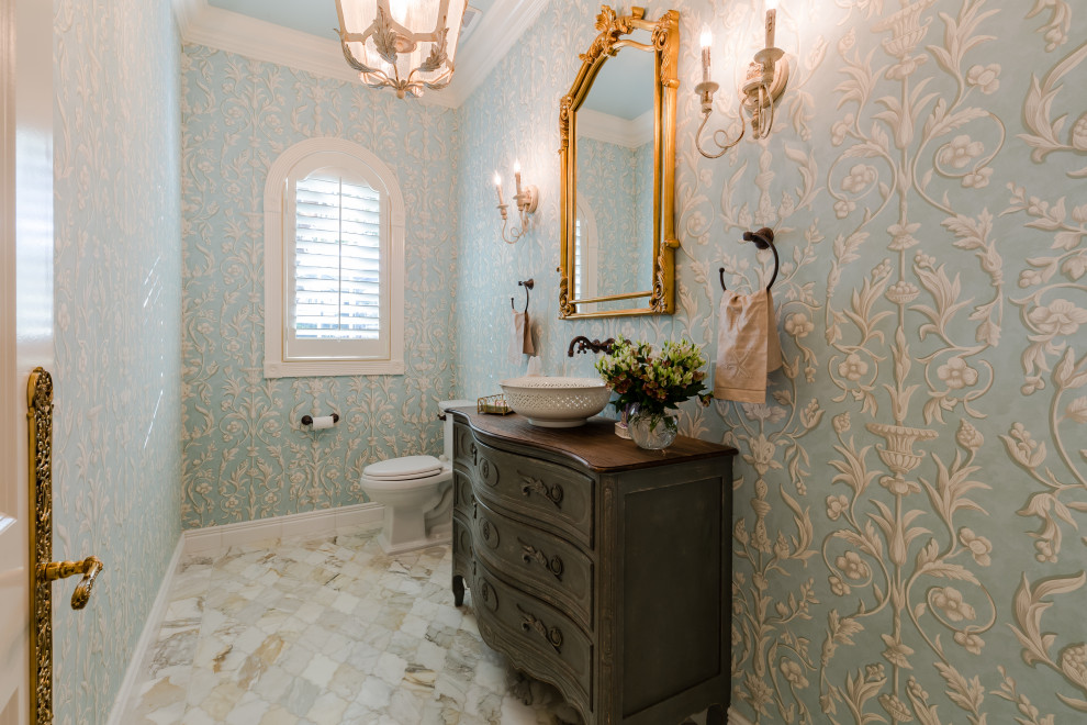 Klassische Gästetoilette mit verzierten Schränken, dunklen Holzschränken, blauer Wandfarbe, Aufsatzwaschbecken, Waschtisch aus Holz, weißem Boden und brauner Waschtischplatte in Miami