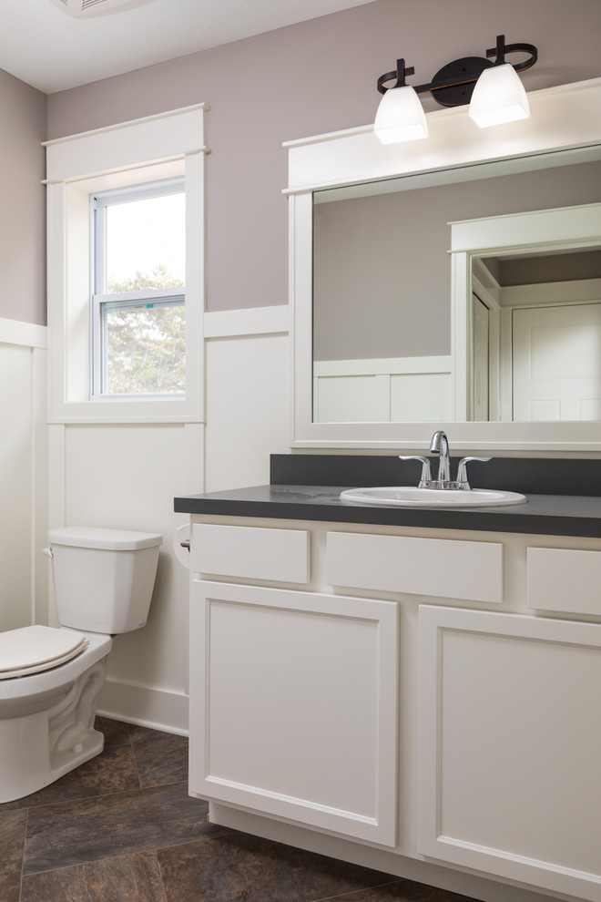 Источник вдохновения для домашнего уюта: туалет среднего размера в стиле кантри с плоскими фасадами, белыми фасадами, унитазом-моноблоком, серыми стенами, полом из ламината, столешницей из ламината и коричневым полом