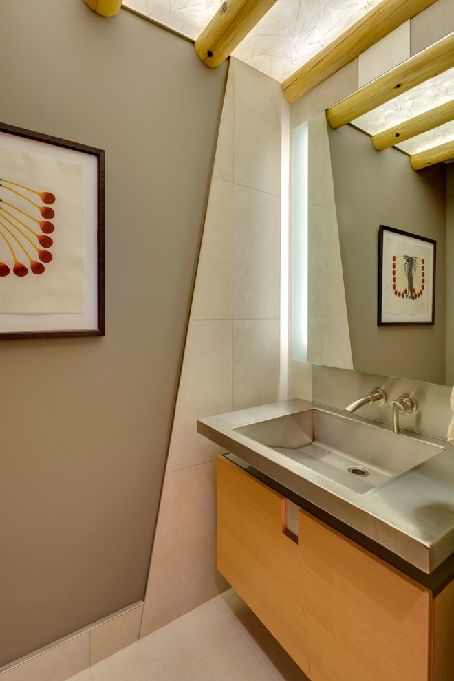 Источник вдохновения для домашнего уюта: туалет в современном стиле с монолитной раковиной, плоскими фасадами, фасадами цвета дерева среднего тона, столешницей из нержавеющей стали и серыми стенами