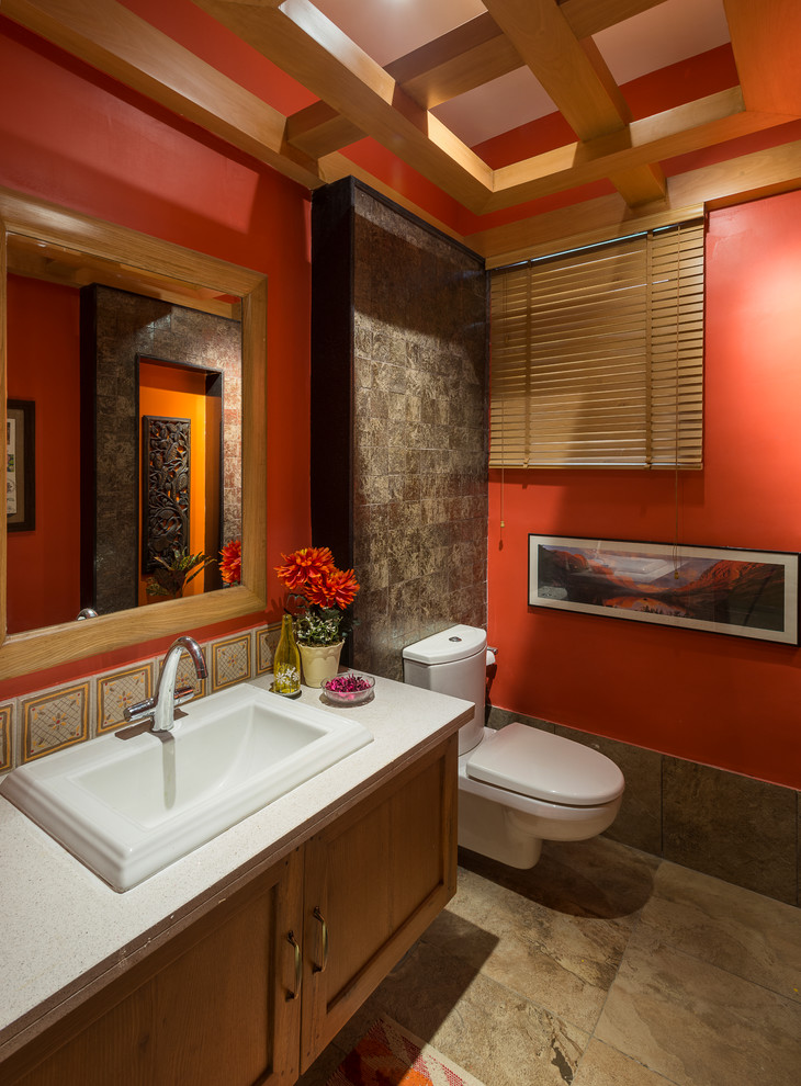 バンガロールにある小さなアジアンスタイルのおしゃれなトイレ・洗面所 (分離型トイレ、赤い壁、大理石の床、オーバーカウンターシンク、御影石の洗面台、茶色い床、落し込みパネル扉のキャビネット、中間色木目調キャビネット) の写真