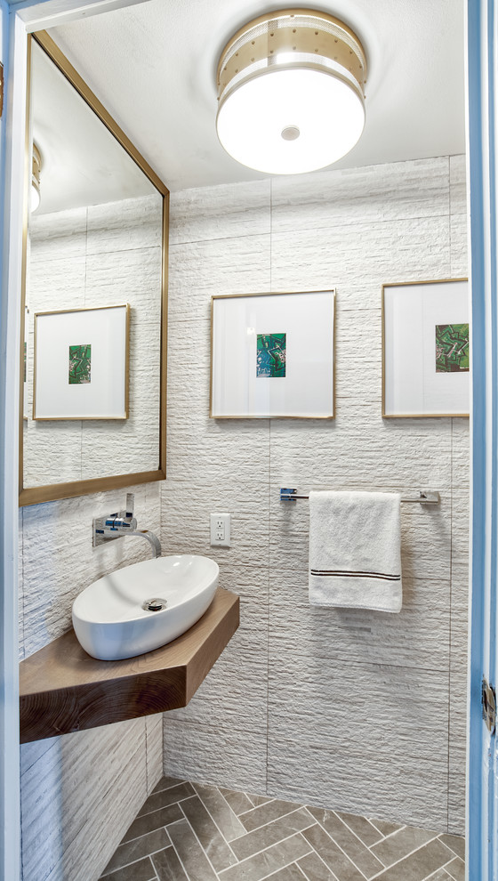 ニューヨークにある高級な小さなトランジショナルスタイルのおしゃれなトイレ・洗面所 (セラミックタイル、大理石の床、ベッセル式洗面器、木製洗面台、グレーの床、ブラウンの洗面カウンター、白いタイル) の写真