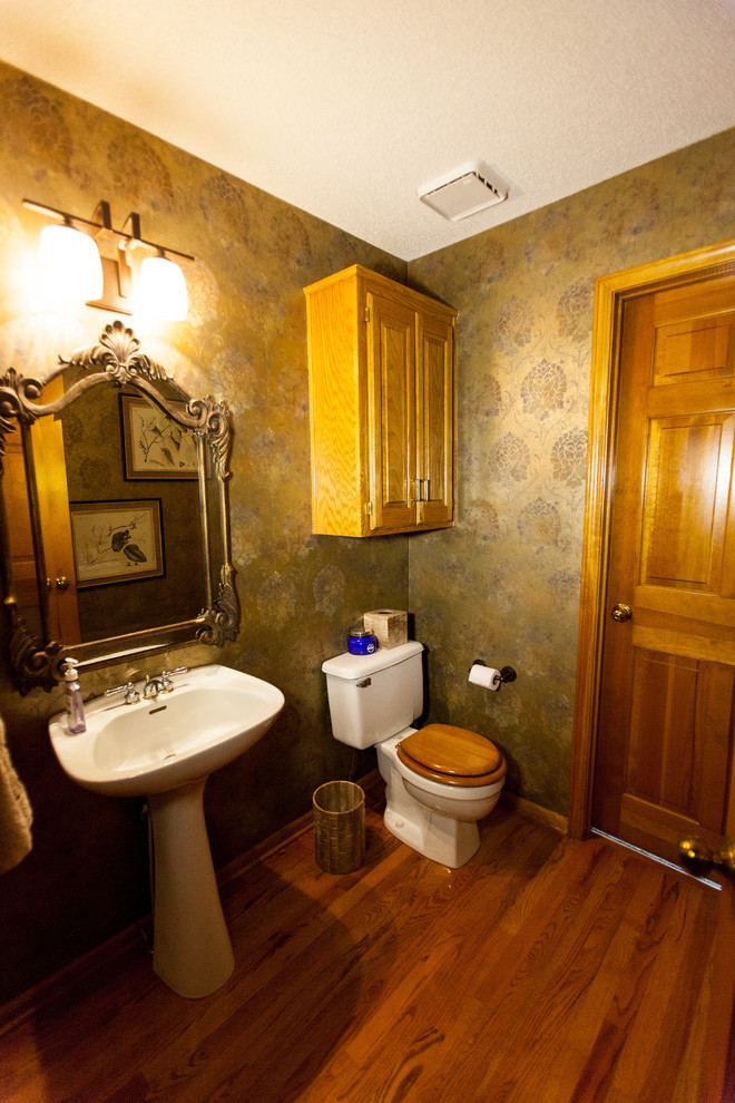 Пример оригинального дизайна: туалет среднего размера в классическом стиле с фасадами с выступающей филенкой, светлыми деревянными фасадами, раздельным унитазом, разноцветными стенами, паркетным полом среднего тона, раковиной с пьедесталом и коричневым полом