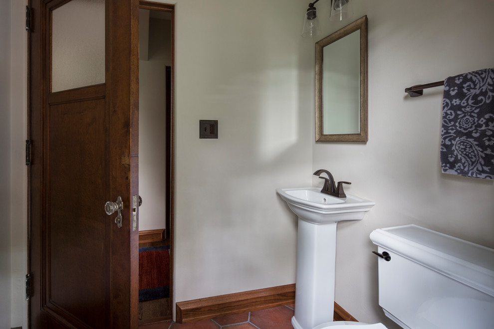 На фото: маленький туалет в классическом стиле с раздельным унитазом, бежевыми стенами, полом из терракотовой плитки, раковиной с пьедесталом и коричневым полом для на участке и в саду с
