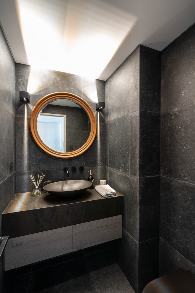 Cette image montre un petit WC suspendu design avec un sol en carrelage de porcelaine, un plan de toilette en quartz modifié, un sol gris, un carrelage gris, des carreaux de porcelaine, un mur gris, une vasque et un plan de toilette marron.