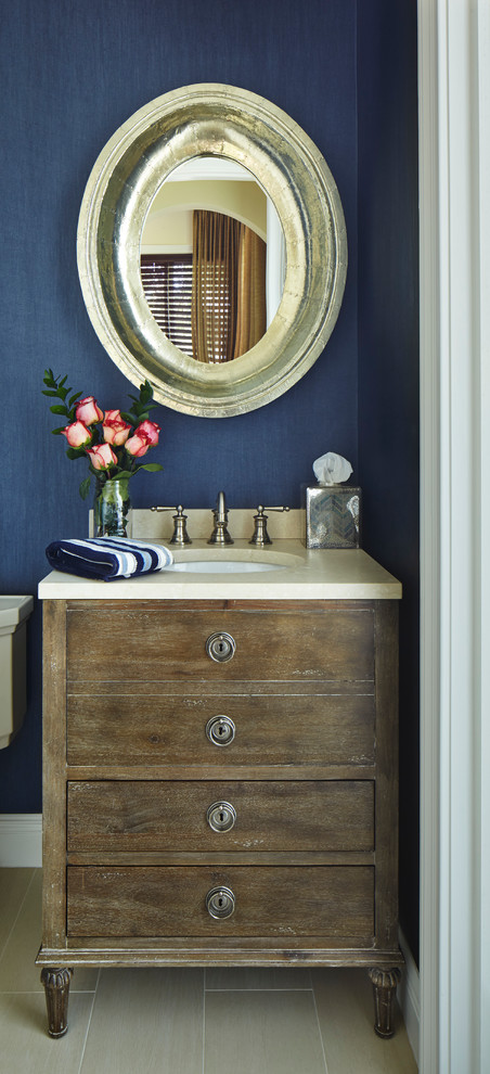 Bild på ett litet rustikt toalett, med ett undermonterad handfat, släta luckor, skåp i slitet trä, marmorbänkskiva, en toalettstol med hel cisternkåpa, blå väggar och klinkergolv i porslin