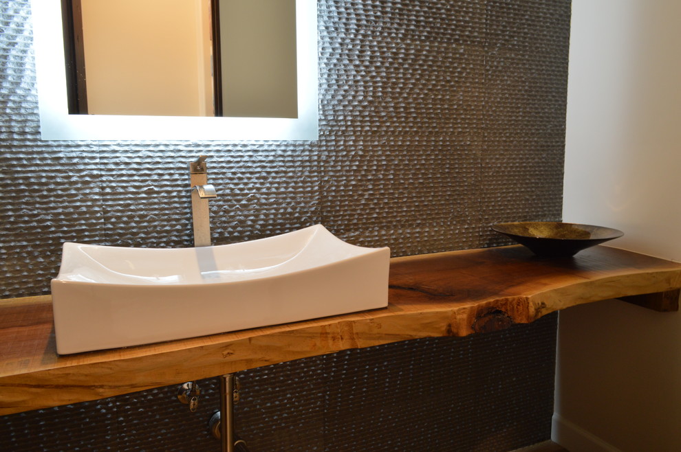 Cette photo montre un petit WC et toilettes éclectique avec une vasque, un plan de toilette en bois, un carrelage gris et un mur gris.