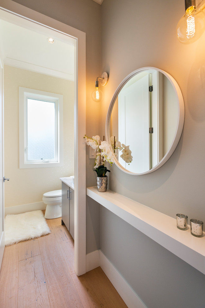 Photo of a small classic cloakroom in Vancouver with flat-panel cabinets, grey cabinets, a two-piece toilet, beige walls, light hardwood flooring, a vessel sink, quartz worktops, beige floors and beige worktops.