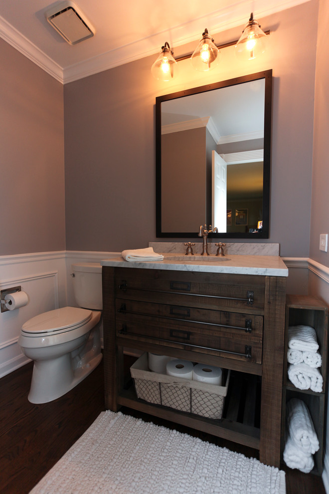 Cette image montre un WC et toilettes rustique en bois foncé de taille moyenne avec un placard en trompe-l'oeil, un mur gris, parquet foncé, un lavabo encastré et un plan de toilette en quartz.
