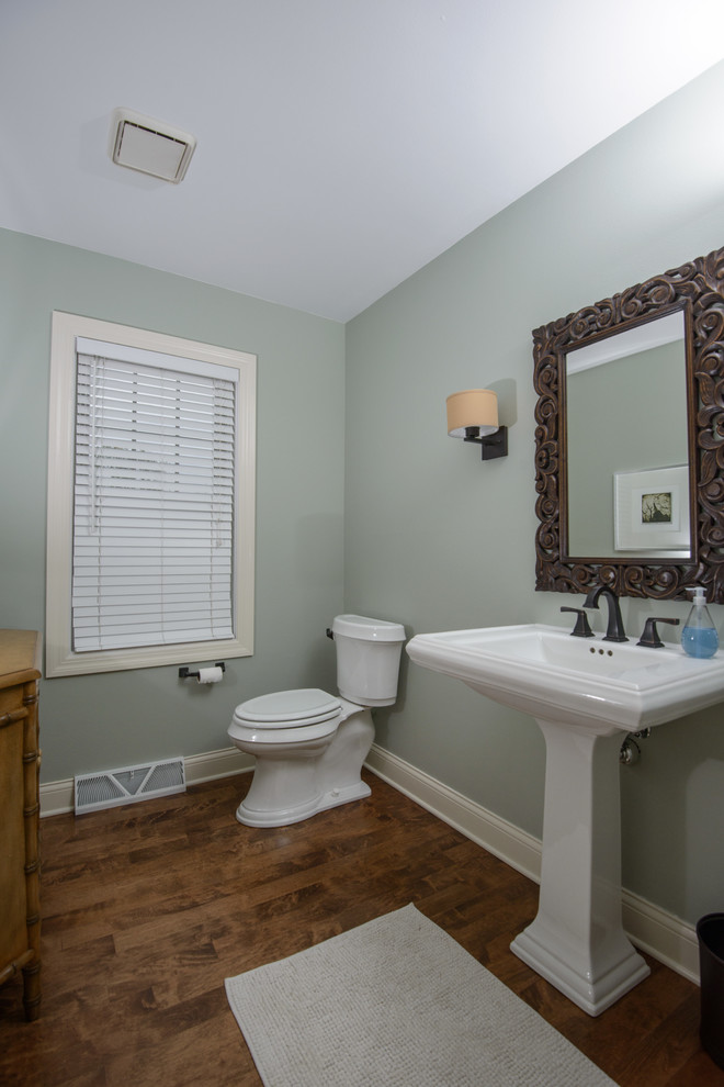 Immagine di un bagno di servizio design di medie dimensioni con lavabo a colonna, pareti verdi e pavimento in legno massello medio