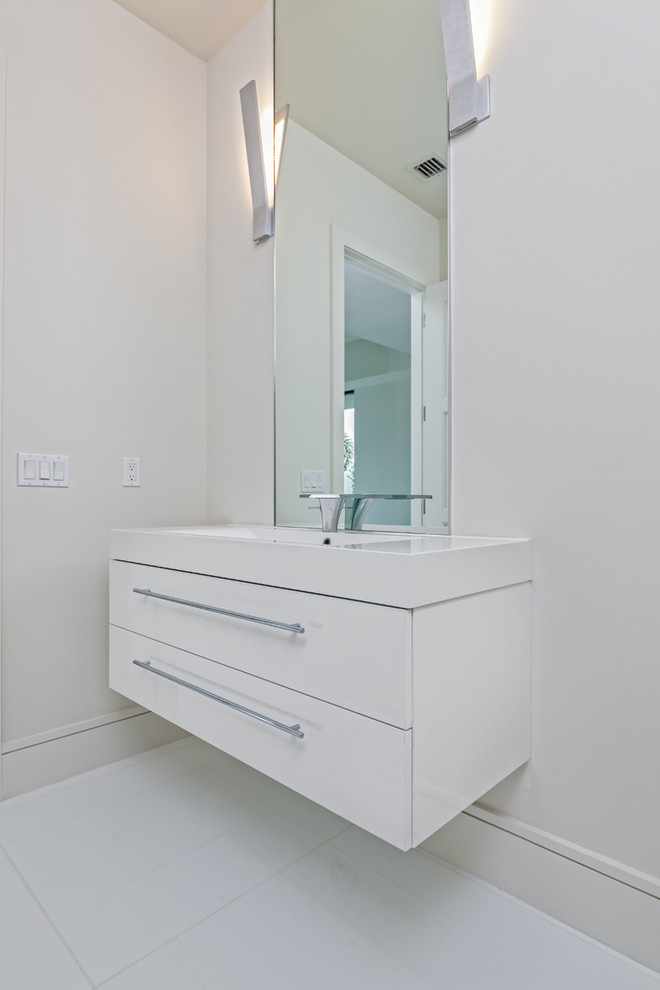 Idée de décoration pour un WC et toilettes minimaliste de taille moyenne avec un placard à porte plane, des portes de placard blanches, un mur blanc, un lavabo intégré, un plan de toilette en quartz modifié, un sol blanc et un plan de toilette blanc.