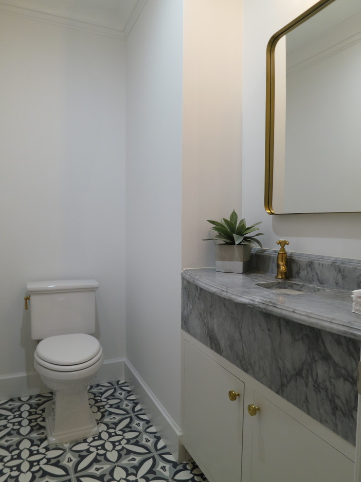 Exemple d'un petit WC et toilettes chic avec un placard à porte plane, des portes de placard blanches, WC séparés, un mur blanc, carreaux de ciment au sol, un lavabo encastré, un plan de toilette en marbre, un sol gris et un plan de toilette gris.