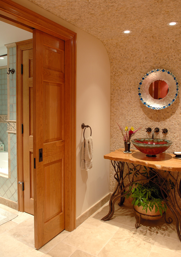 他の地域にあるトラディショナルスタイルのおしゃれなトイレ・洗面所 (ベッセル式洗面器、木製洗面台、ベージュのタイル、ベージュの壁、トラバーチンの床、石スラブタイル、ブラウンの洗面カウンター) の写真
