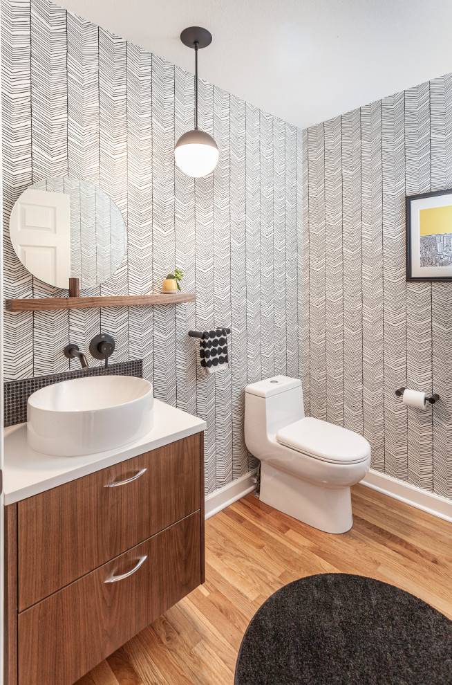 Inspiration for a small retro cloakroom in Detroit with flat-panel cabinets, brown cabinets, a one-piece toilet, black and white tiles, ceramic tiles, light hardwood flooring, a vessel sink, engineered stone worktops, brown floors, white worktops, a floating vanity unit and wallpapered walls.