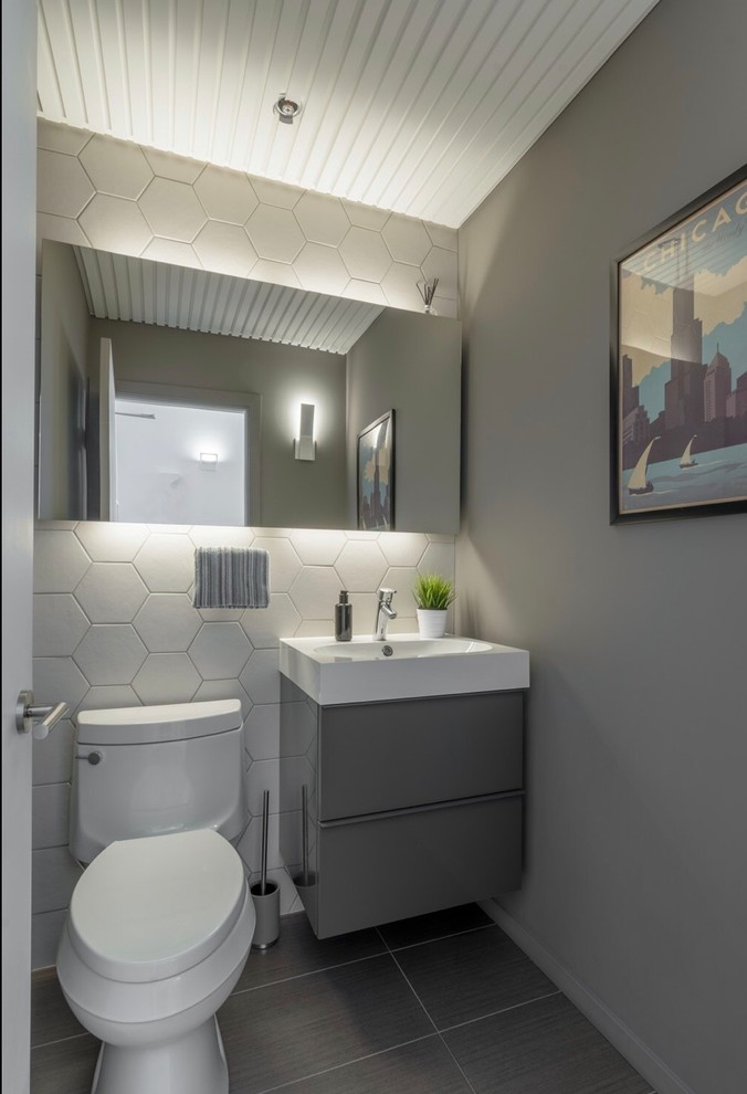 This is an example of a medium sized modern cloakroom in Chicago with flat-panel cabinets, grey cabinets, a one-piece toilet, beige tiles, ceramic tiles, grey walls, porcelain flooring, engineered stone worktops, grey floors and white worktops.