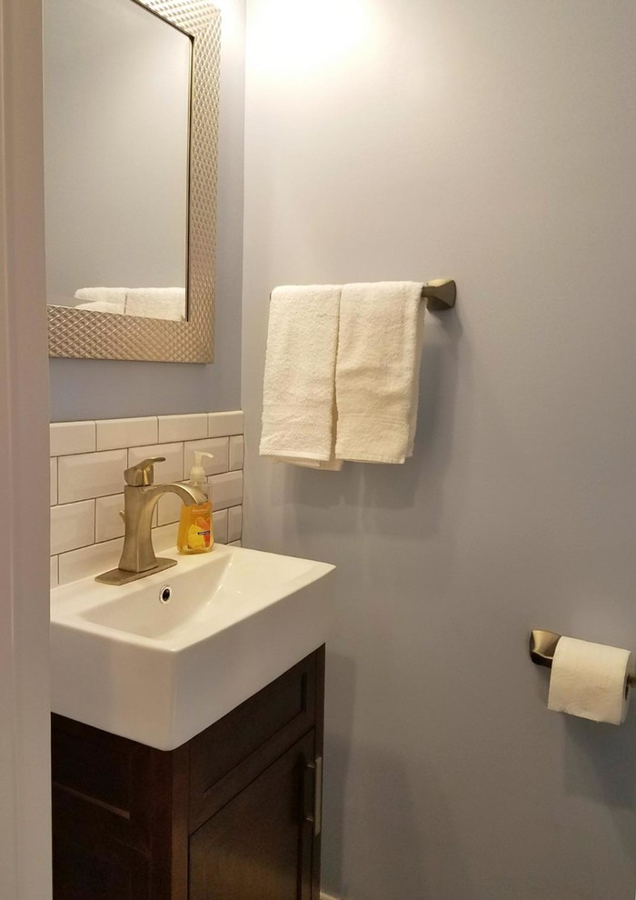Cette image montre un petit WC et toilettes traditionnel en bois foncé avec un placard en trompe-l'oeil, un carrelage blanc, un carrelage métro, un mur gris, un lavabo intégré, un plan de toilette en quartz modifié et un plan de toilette blanc.