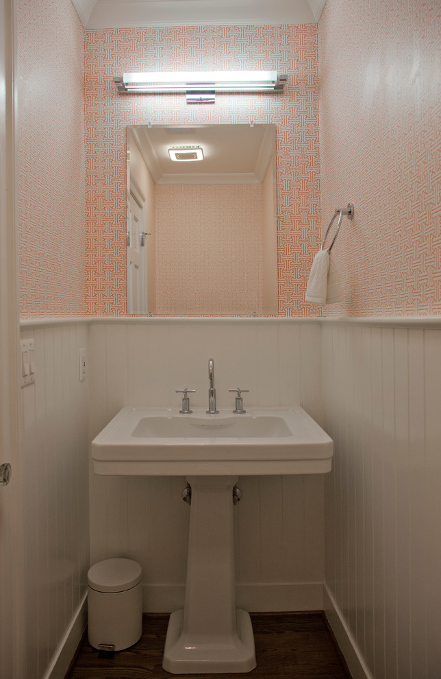 Immagine di un piccolo bagno di servizio classico con pareti arancioni, parquet scuro, lavabo a colonna, pavimento marrone, top in superficie solida e top bianco
