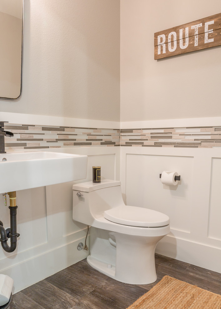Modern inredning av ett mellanstort vit vitt toalett, med släta luckor, vita skåp, grå kakel, glaskakel, grå väggar, laminatgolv, ett väggmonterat handfat, bänkskiva i kvarts och grått golv