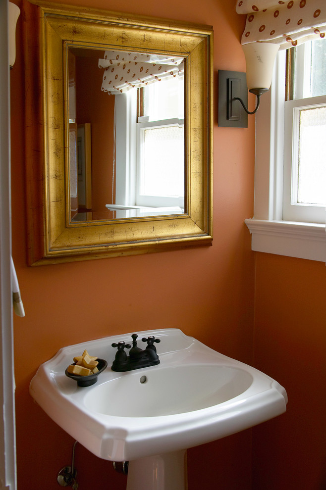 Inspiration för mellanstora klassiska toaletter, med ett fristående handfat, orange väggar och mellanmörkt trägolv