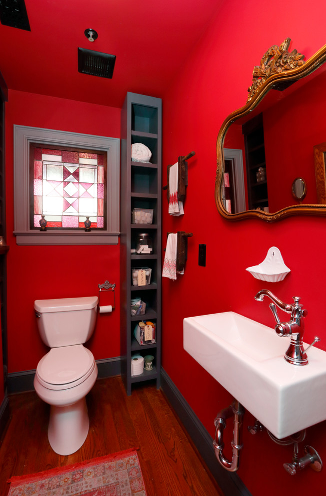 Example of a small eclectic medium tone wood floor powder room design in Other with open cabinets, gray cabinets, a two-piece toilet, red walls and a wall-mount sink