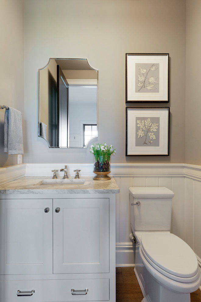This is an example of a medium sized beach style cloakroom in Minneapolis with freestanding cabinets, white cabinets, beige walls, medium hardwood flooring, a built-in sink, engineered stone worktops, brown floors and white worktops.