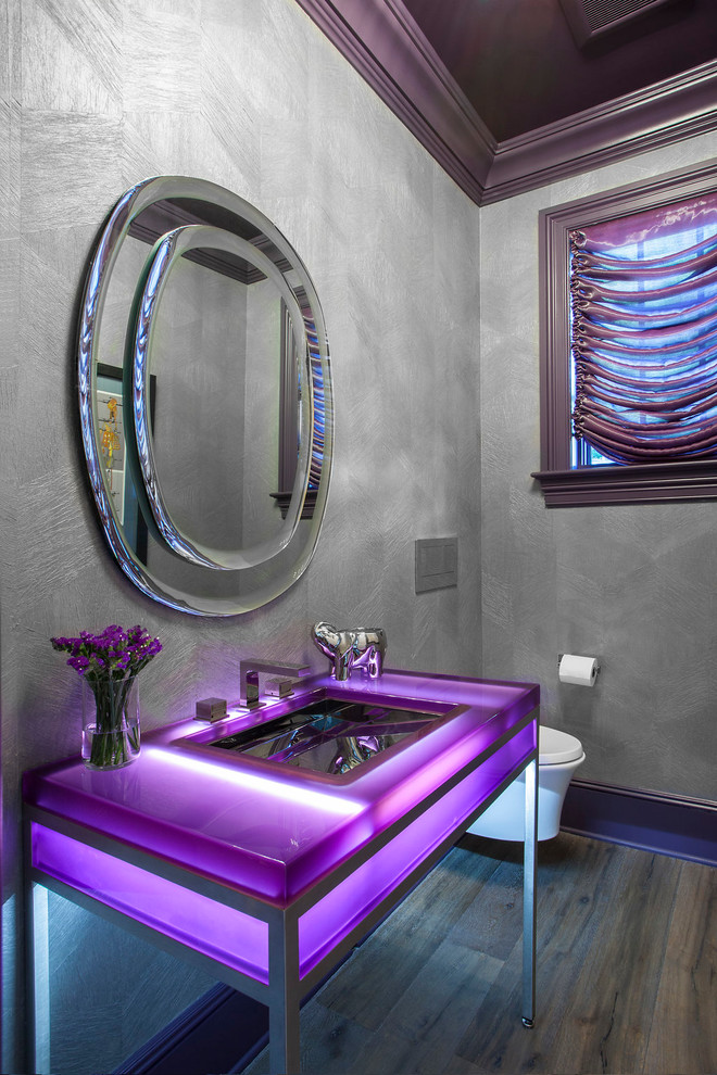 Idéer för att renovera ett mellanstort funkis lila lila toalett, med en vägghängd toalettstol, grå väggar, mörkt trägolv, ett konsol handfat och brunt golv
