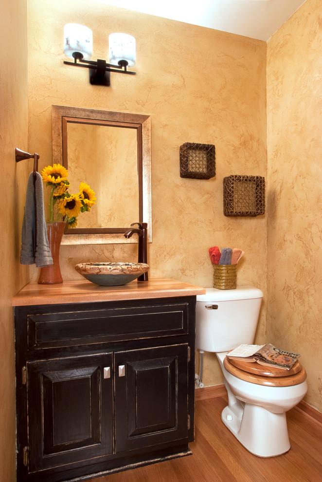 Idées déco pour un WC et toilettes classique en bois foncé avec une vasque, un placard avec porte à panneau surélevé, un mur beige et un sol en bois brun.