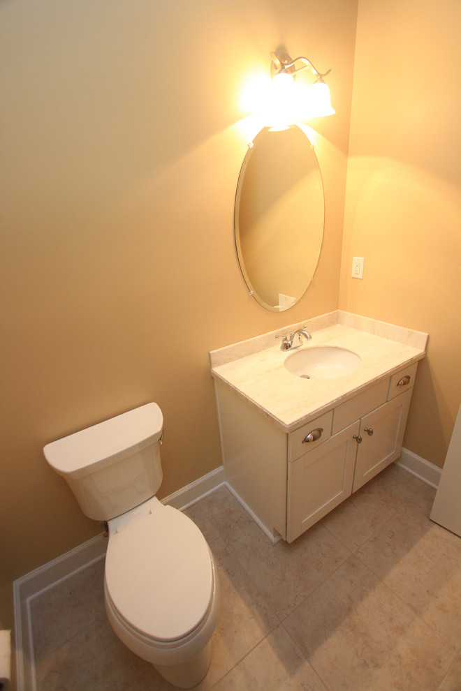 Rustik inredning av ett toalett, med ett undermonterad handfat, skåp i shakerstil, vita skåp, bänkskiva i akrylsten och en toalettstol med separat cisternkåpa
