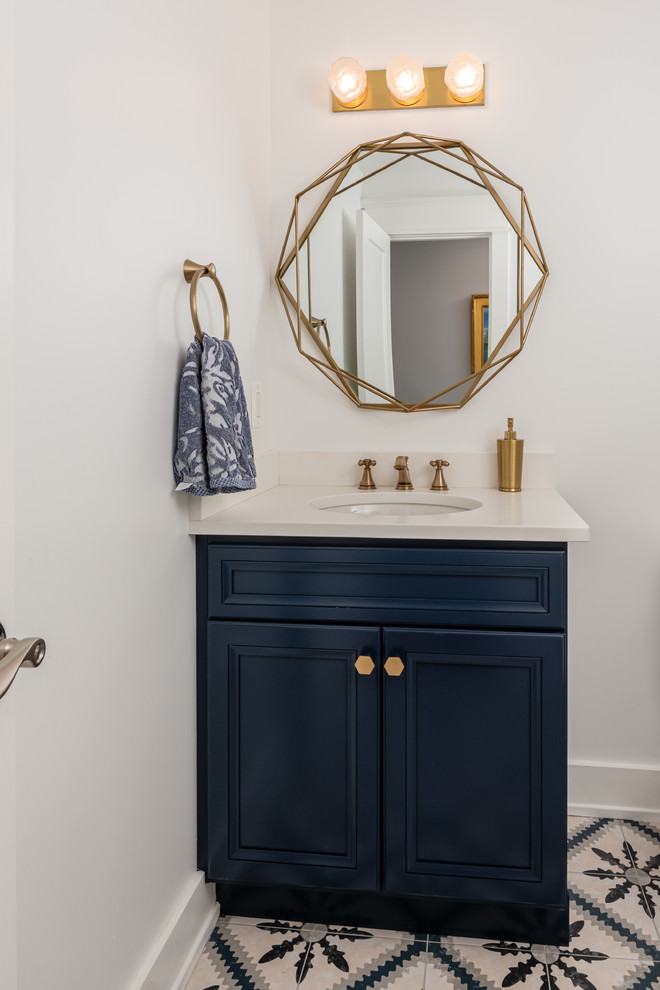 Bild på ett mellanstort vintage toalett, med luckor med infälld panel, blå skåp, en toalettstol med separat cisternkåpa, ett undermonterad handfat, flerfärgat golv, vita väggar och bänkskiva i kvarts