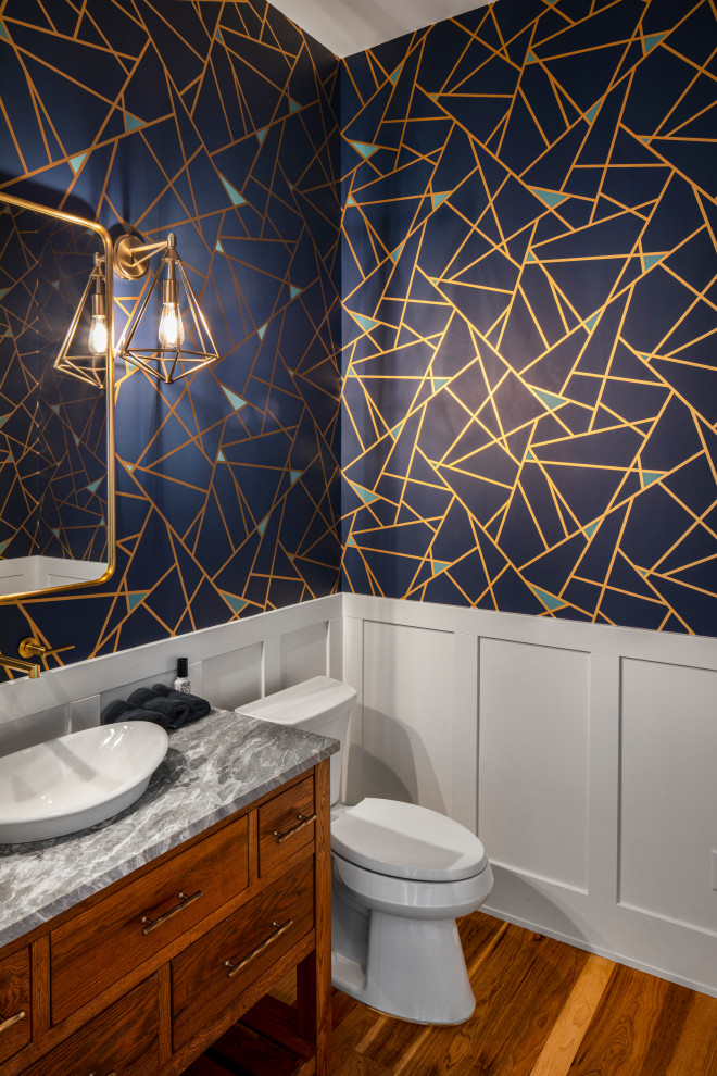 Cette photo montre un WC et toilettes nature en bois brun avec un placard en trompe-l'oeil, un mur bleu, un sol en bois brun, une vasque, un plan de toilette en marbre, un sol marron, un plan de toilette gris et meuble-lavabo encastré.