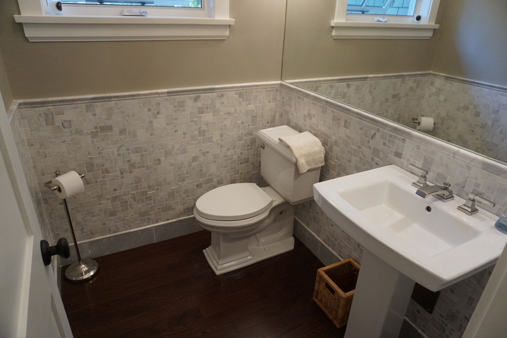 Idéer för ett amerikanskt toalett, med en toalettstol med separat cisternkåpa, mörkt trägolv och ett piedestal handfat