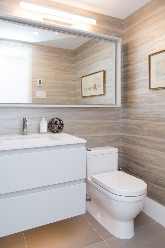 Foto på ett litet funkis vit toalett, med släta luckor, vita skåp, en toalettstol med hel cisternkåpa, beige väggar, klinkergolv i porslin, ett undermonterad handfat, bänkskiva i akrylsten och beiget golv