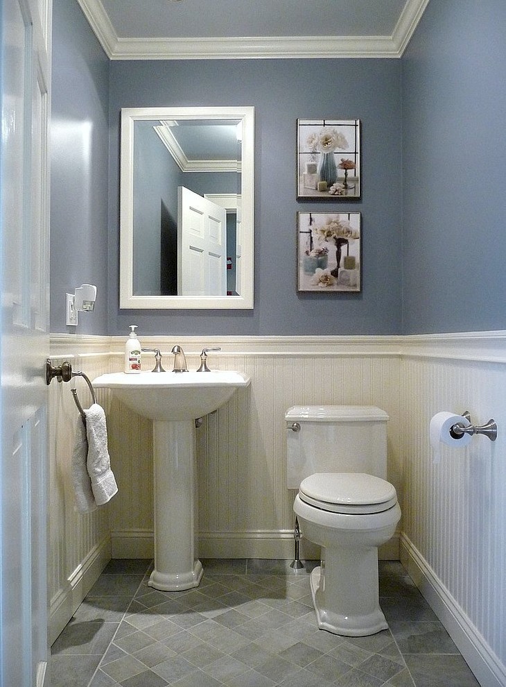 Foto på ett litet vintage toalett, med ett piedestal handfat, en toalettstol med separat cisternkåpa, blå väggar, klinkergolv i porslin och grå kakel