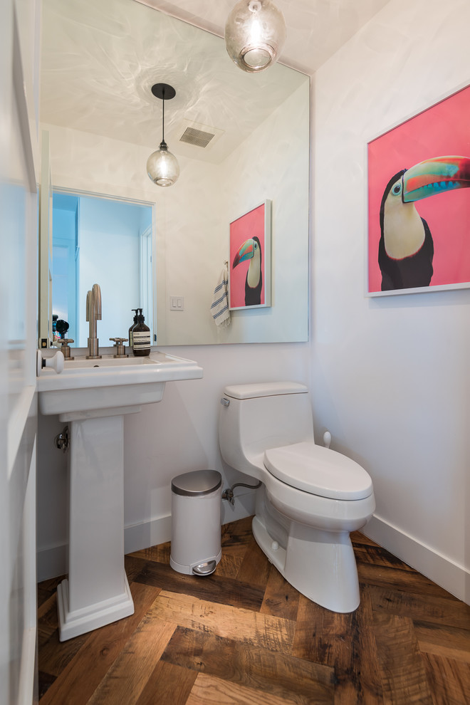 Immagine di un bagno di servizio moderno di medie dimensioni con WC monopezzo, pareti bianche, pavimento in legno massello medio, lavabo a colonna e pavimento marrone