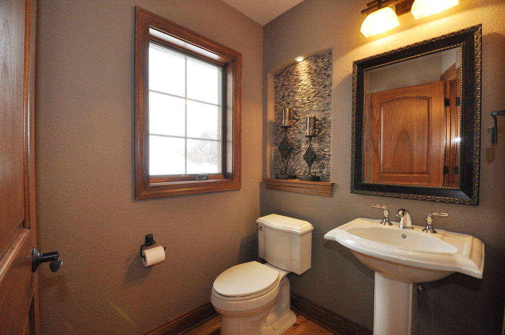 Small traditional cloakroom in Milwaukee with a pedestal sink, a two-piece toilet, grey tiles, glass tiles, beige walls and medium hardwood flooring.
