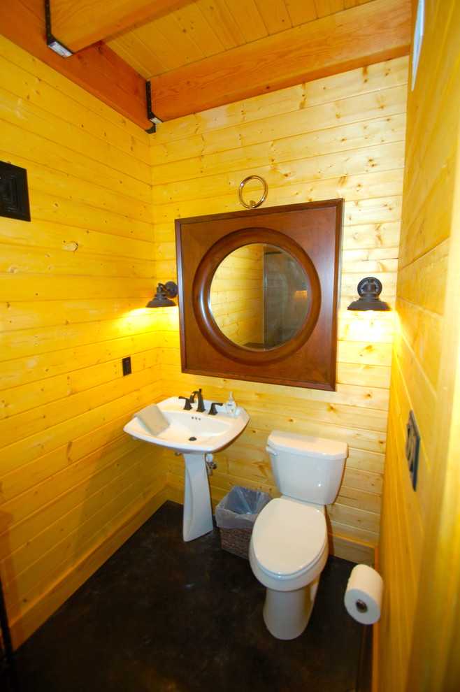 На фото: маленький туалет в классическом стиле с раздельным унитазом, коричневыми стенами, бетонным полом, раковиной с пьедесталом и черным полом для на участке и в саду