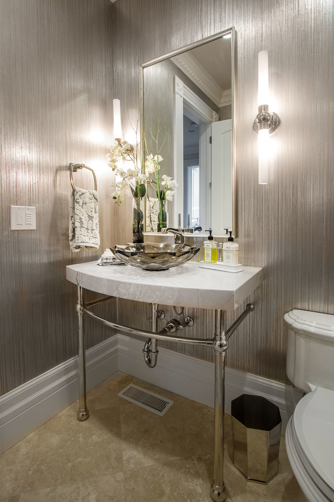 Foto på ett stort vintage grå toalett, med en toalettstol med separat cisternkåpa, grå kakel, grå väggar, travertin golv, ett konsol handfat, marmorbänkskiva och brunt golv