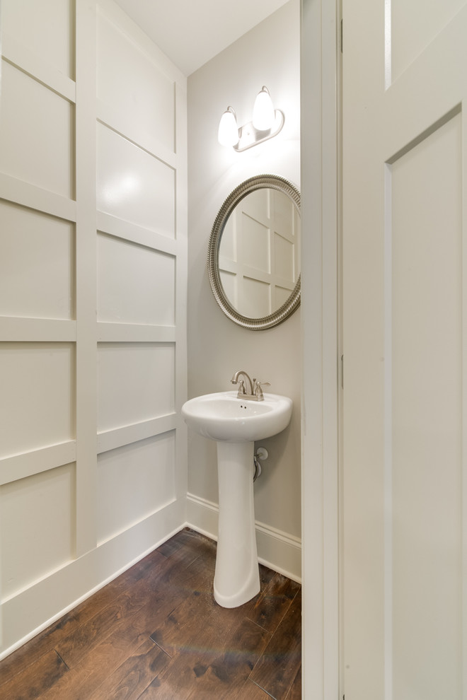 Kleine Klassische Gästetoilette mit grauer Wandfarbe, dunklem Holzboden, Sockelwaschbecken und braunem Boden in Sonstige