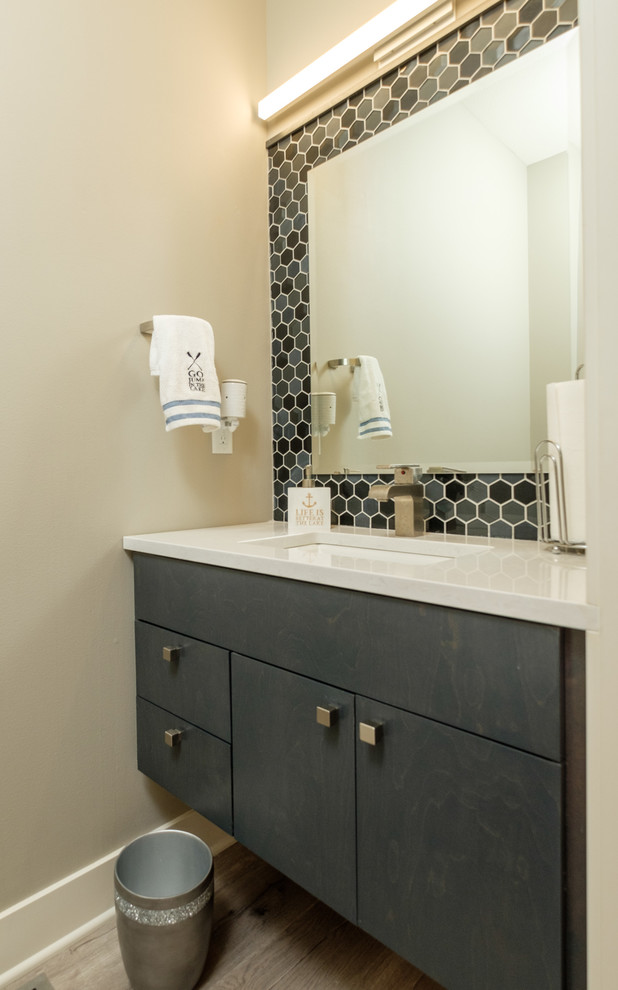 Example of a trendy porcelain tile medium tone wood floor powder room design in Other with furniture-like cabinets, gray cabinets, an undermount sink, quartz countertops, beige walls and white countertops