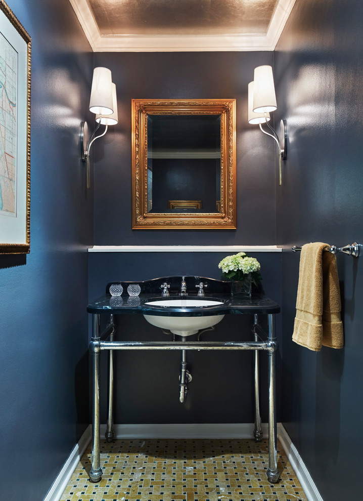 Modelo de aseo clásico renovado con paredes azules, suelo con mosaicos de baldosas, lavabo bajoencimera, suelo marrón y encimeras negras