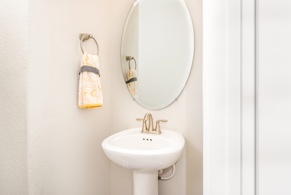 Modern inredning av ett mellanstort toalett, med vita skåp, en toalettstol med hel cisternkåpa, vit kakel, vita väggar, ett piedestal handfat, skåp i shakerstil och bänkskiva i akrylsten
