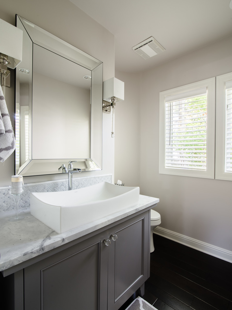 Small traditional cloakroom in Seattle with freestanding cabinets, grey cabinets, a one-piece toilet, grey tiles, marble tiles, grey walls, dark hardwood flooring, a vessel sink, quartz worktops and brown floors.