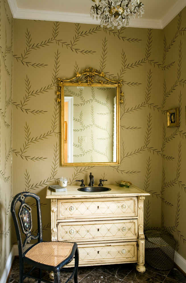 Inredning av ett klassiskt litet toalett, med möbel-liknande, beige skåp, flerfärgade väggar, ett nedsänkt handfat, brunt golv, en toalettstol med hel cisternkåpa och träbänkskiva