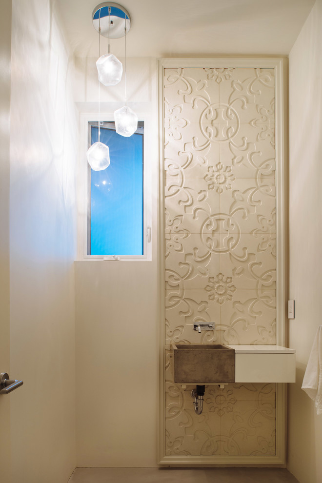 Foto di un piccolo bagno di servizio minimal con ante lisce, ante bianche, piastrelle bianche, pareti bianche, pavimento in cemento, lavabo sospeso e pavimento grigio