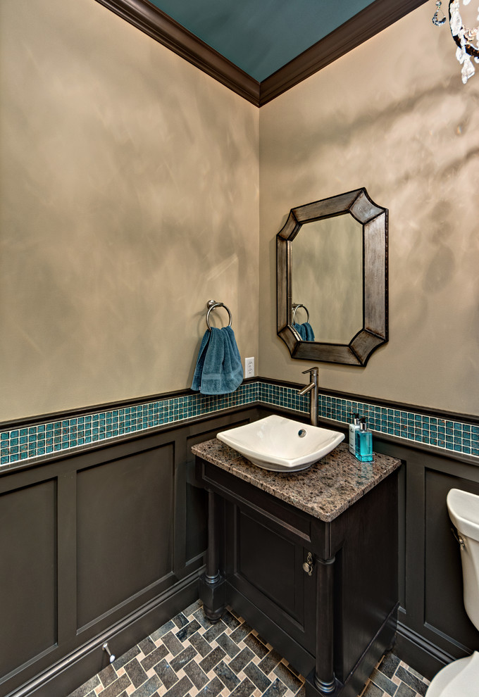 Inspiration for a medium sized classic cloakroom in Minneapolis with flat-panel cabinets, dark wood cabinets, a two-piece toilet, blue tiles, glass sheet walls, beige walls, mosaic tile flooring, a vessel sink, granite worktops and brown floors.