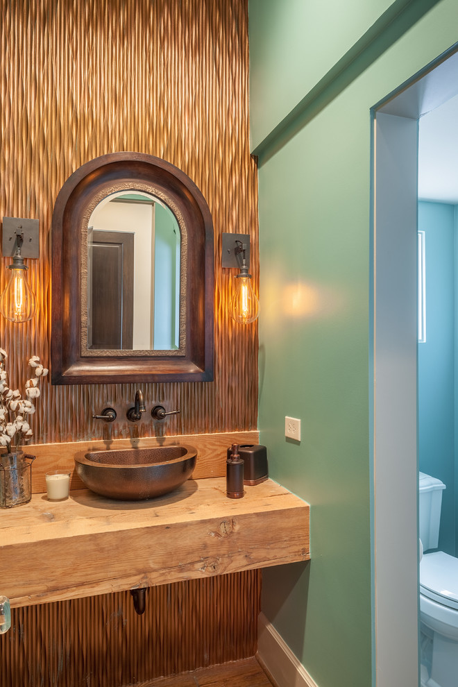 На фото: туалет с светлыми деревянными фасадами, зеленой плиткой, металлической плиткой, зелеными стенами и столешницей из дерева с
