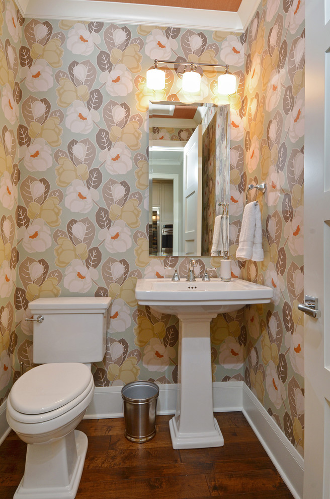 На фото: туалет в классическом стиле с раковиной с пьедесталом, раздельным унитазом, разноцветными стенами и темным паркетным полом с