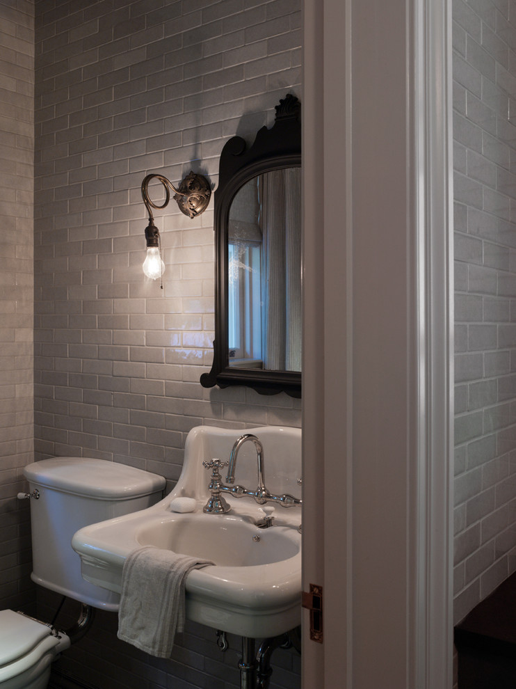 Modelo de aseo tradicional con lavabo tipo consola, baldosas y/o azulejos de cerámica, paredes blancas y baldosas y/o azulejos grises