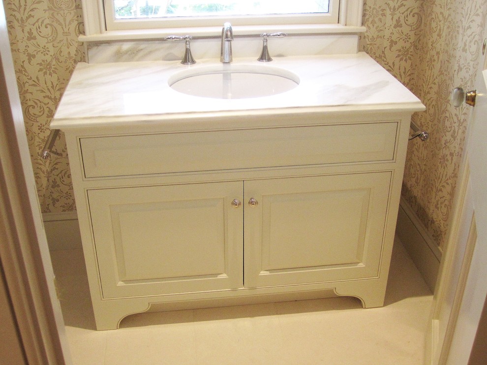 Esempio di un piccolo bagno di servizio classico con lavabo sottopiano, ante a filo, top in marmo e ante beige