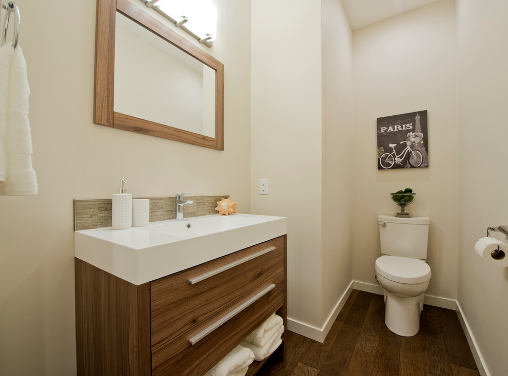 バンクーバーにあるコンテンポラリースタイルのおしゃれなトイレ・洗面所 (フラットパネル扉のキャビネット、中間色木目調キャビネット、濃色無垢フローリング、一体型シンク、茶色い床、白い洗面カウンター) の写真