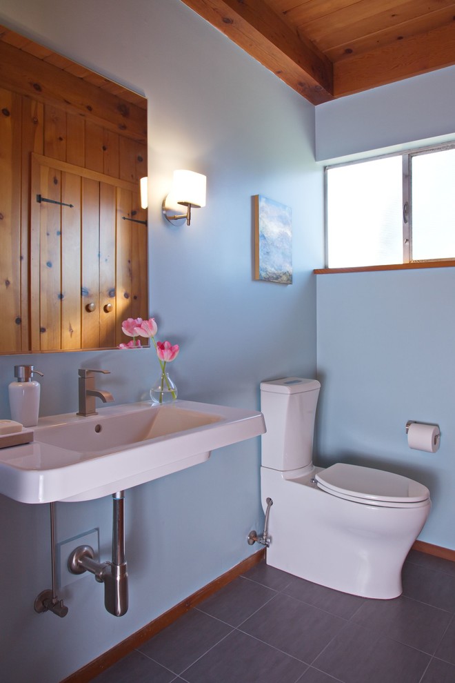 Foto på ett mellanstort 60 tals toalett, med en toalettstol med hel cisternkåpa, blå väggar, klinkergolv i porslin, ett väggmonterat handfat och grått golv